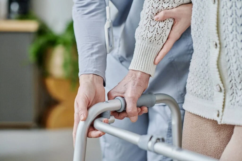 Caregiver helping a senior hold a walker handle safely