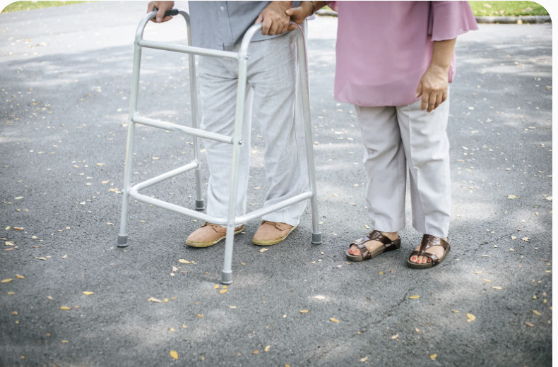 Senior using a small walker with a caregiver nearby