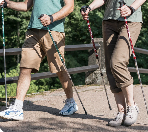 Two people walking outdoors with trekking poles for support