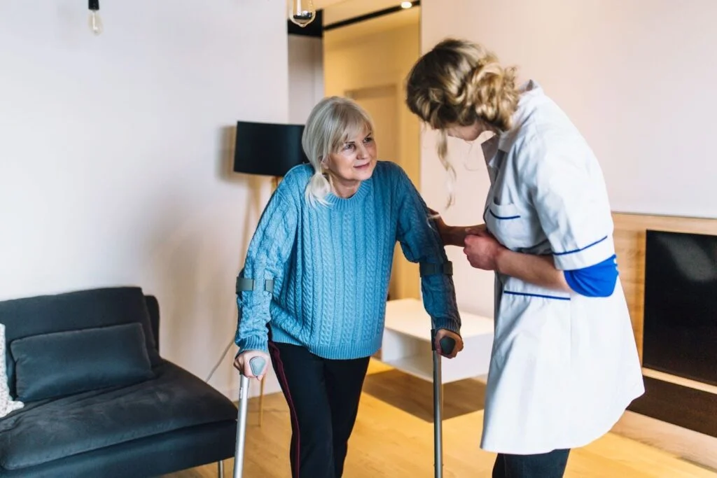 Caregiver assisting senior woman with walking support in a home environment
